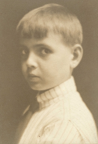 Warm toned black and white photo portrait of a young boy, 3/4 view and looking a the camera, circa 1920.