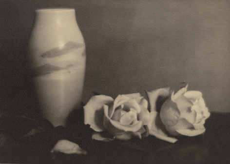 Black and white photo of a vase decorated with Japanese koi, two roses sit next to the vase on the right.