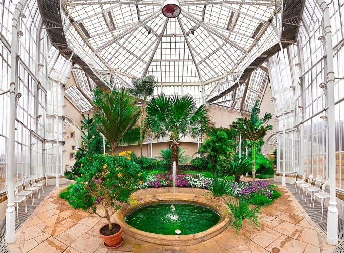 Composite, panaromic type photo, of a greenhouse interior with a green fountain.